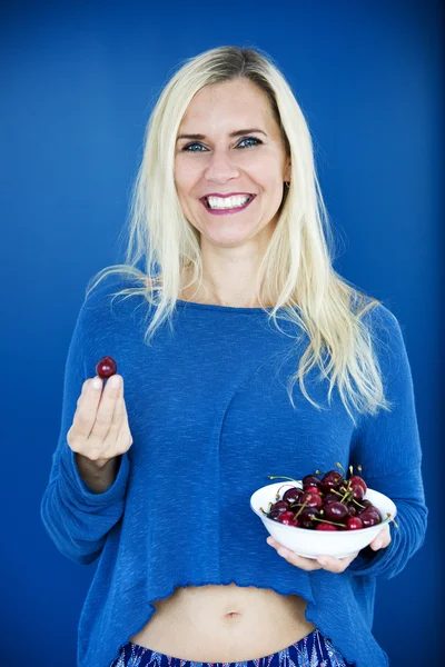Blond woman eating cherries — Stock Photo, Image