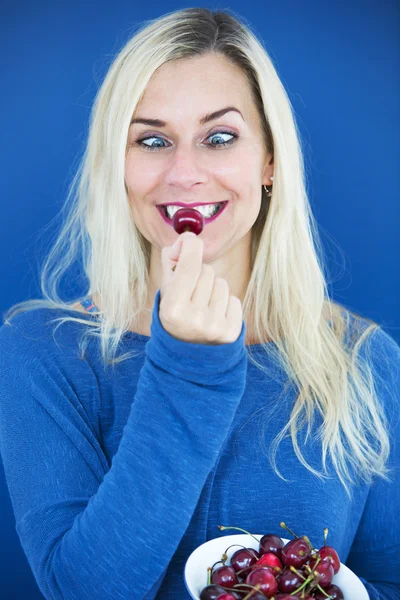 Blond cross-eyed woman eating a cherry — Stock Photo, Image