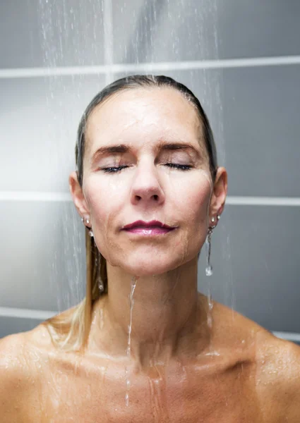Mujer rubia tomando una ducha con los ojos cerrados — Foto de Stock