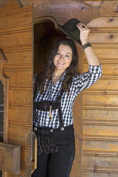 Vrouw in lederhosen permanent op een deur — Stockfoto