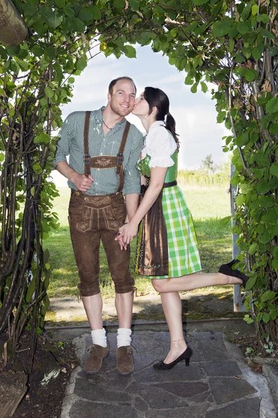 Bavarian girl giving her boyfriend a kiss — Stock Photo, Image