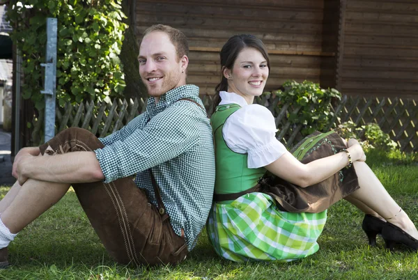 Bavorské pár sedící v trávě — Stock fotografie