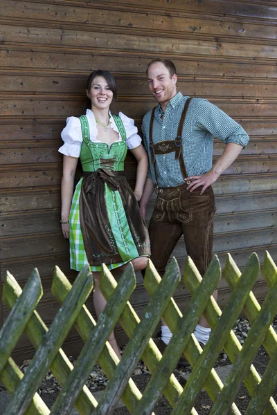 Bavarian couple standing behind a wooden fence — Stock Photo, Image