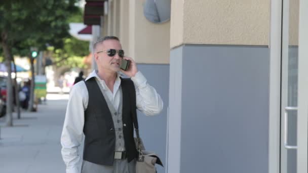 Красивый бизнесмен разговаривает по телефону перед офисным зданием — стоковое видео