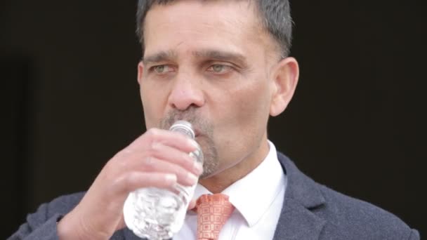 Бизнесмен пьет воду из бутылки — стоковое видео