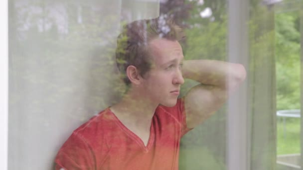 Young blond man looking out of window and holding a cup — Stock Video