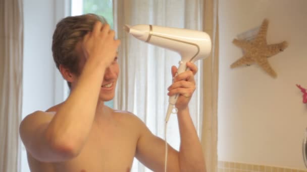 Shirtless jongeman föhnen zijn haar in een badkamer — Stockvideo