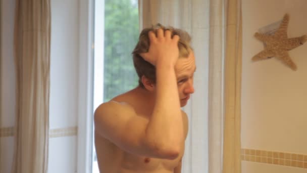 Jeune homme torse nu se lavant le visage dans une salle de bain — Video