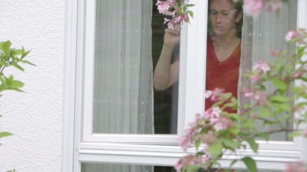 Jovem loiro abre janela e cumprimenta alguém com um sorriso — Vídeo de Stock