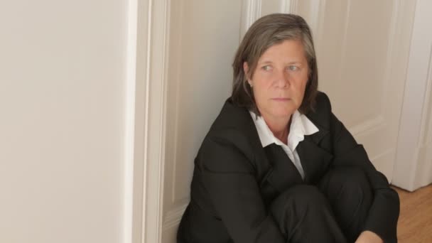 Бізнес-леді в 50 років сидить на підлозі і виглядає дуже пригніченою — стокове відео