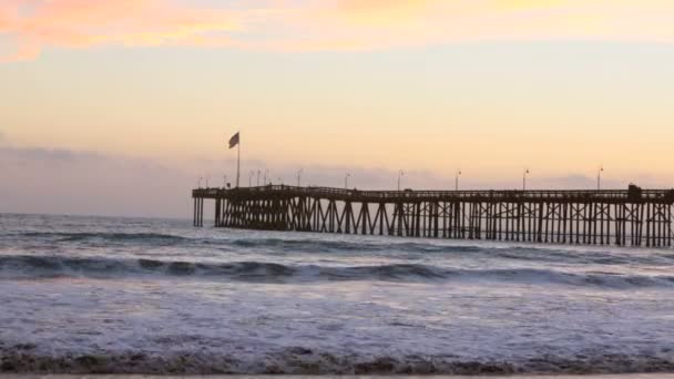 Ventura Pier in Californië bij zonsondergang met de Amerikaanse vlag — Stockvideo