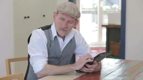 Человек, сидящий за столом в столовой и пишущий своим планшетом — стоковое видео