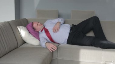 bir kanepe oturma odasında yatan ve bir baş ağrısı olan işadamı
