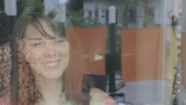 Молодая женщина чистит окно и наслаждается им — стоковое видео