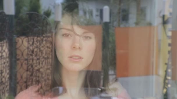 Young woman cleaning a window and looks annoyed through the window at camera — Stock Video