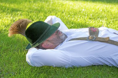 bavarian man sleeping on the grass clipart