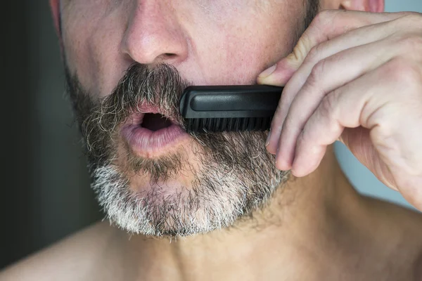 Man borstelen zijn baard — Stockfoto