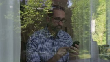 adam arkasında, bir pencere, telefonuna mesaj