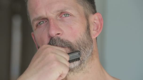 Красивий чоловік чистить свою бороду — стокове відео