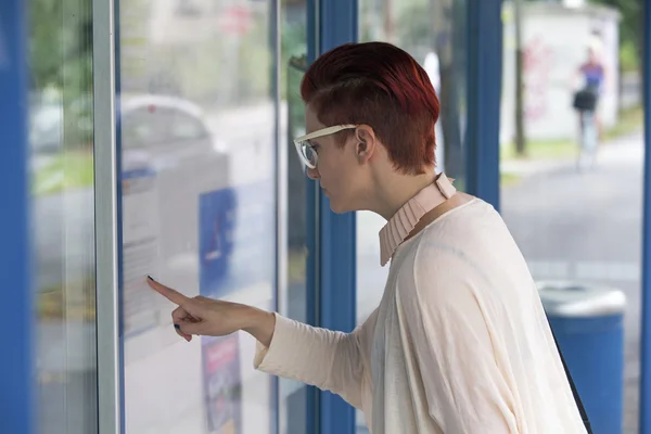 Vrouw bij bus halte kijken naar tijdschema — Stockfoto