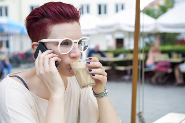 Roodharige vrouw koffie drinken en praten over de telefoon Stockfoto