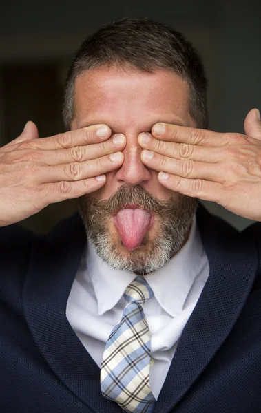 Hombre de negocios cubriendo sus ojos y sacando su lengua —  Fotos de Stock