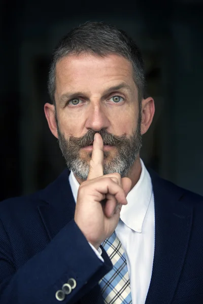 Portrait of handsome businessman with finger to his mouth — Stock fotografie