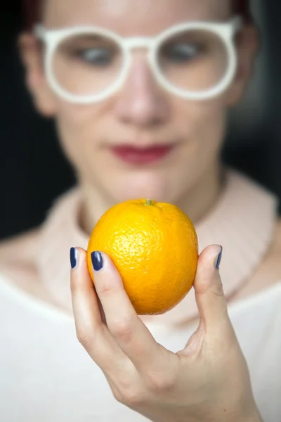 Mulher segurando uma laranja na mão — Fotografia de Stock