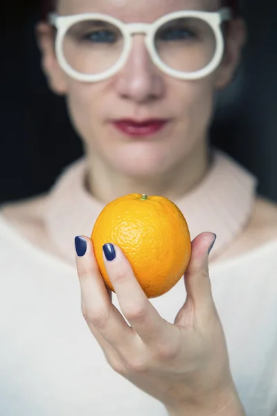 Mulher segurando uma laranja na mão — Fotografia de Stock