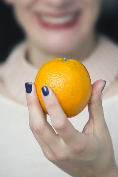 Woman holding an orange in her hand — Stock Photo, Image