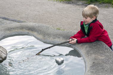 Çeşmede oynayan genç çocuk