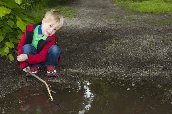 Young boy playing at a puddle — Stock Photo, Image