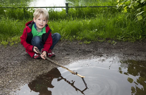 Young boy playing at a puddle — Stock Photo, Image