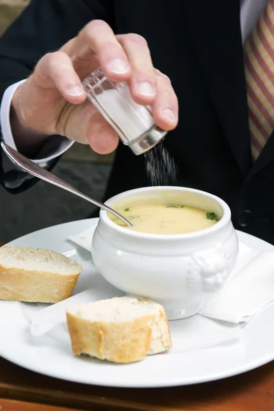 Primer plano del hombre poniendo sal en un tazón de sopa — Foto de Stock