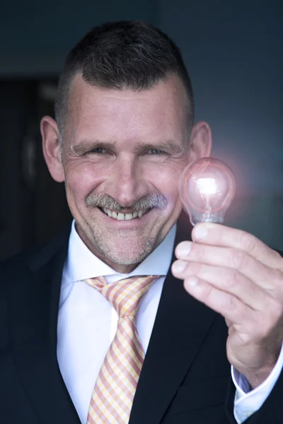 Man holding a lightbulb and smiles — Stock Photo, Image