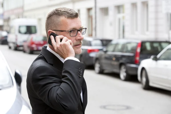 Businessman with phone in the street — Stock Photo, Image