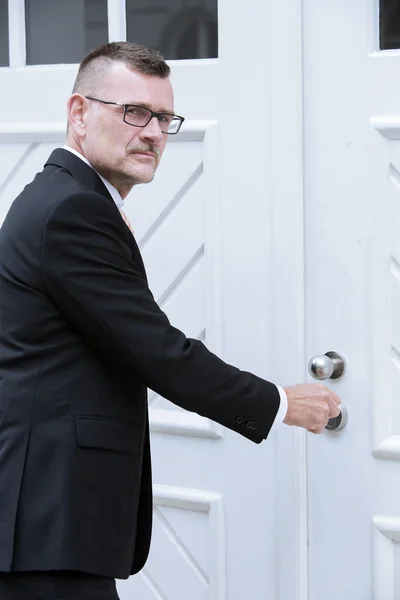 Hombre de traje de pie en la puerta con llave — Foto de Stock