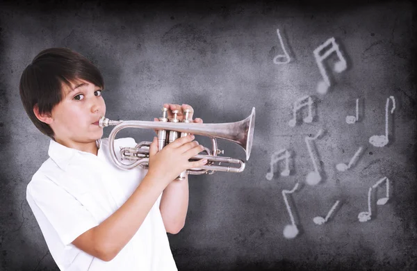 Pojke framför svarta tavlan spela trumpet — Stockfoto