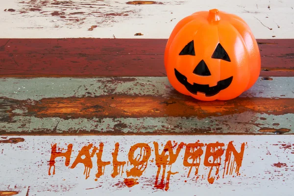 Smiling pumpkin on table with word 'Halloween' — Stock fotografie