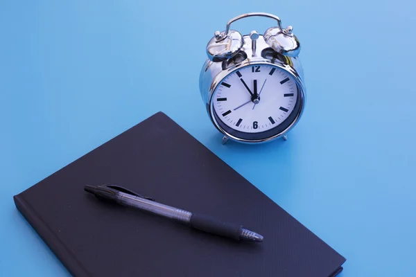 Alarm clock with notepad and pen — Stock Photo, Image