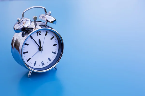 Alarm clock on blue table Stock Photo