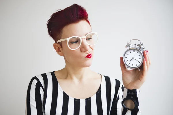 Red-haired woman holding alarm clock looking upset — Stock Photo, Image