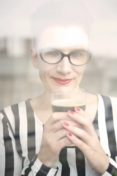 Žena za okno drží sklenici kávy — Stock fotografie