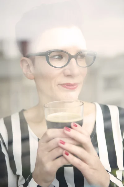 Mulher atrás da janela segurando um copo de café — Fotografia de Stock