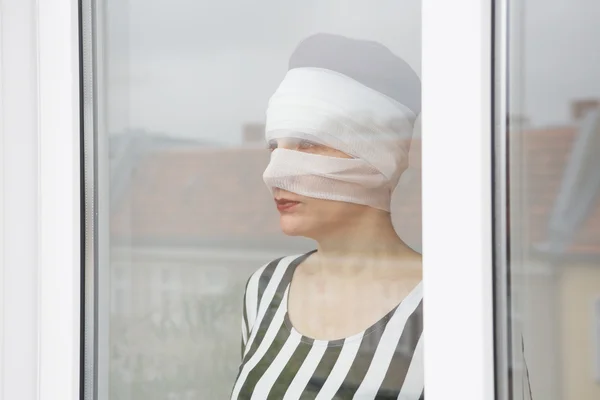 Donna in bende che guarda fuori da una finestra — Foto Stock