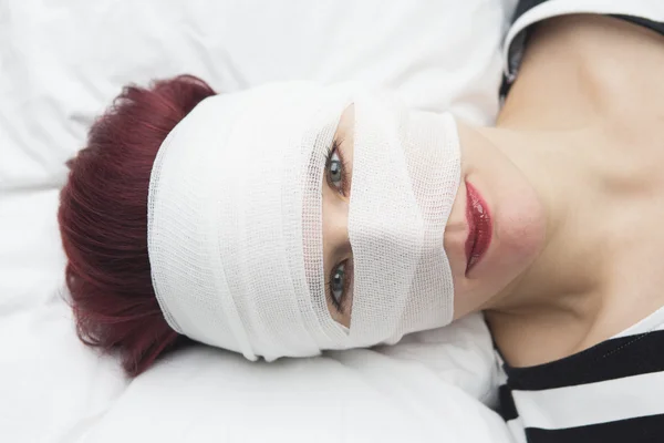 Nahaufnahme einer Frau im Bett mit Binden um den Kopf gewickelt — Stockfoto