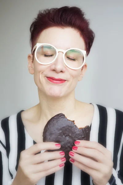 Roodharige vrouw eten een grote chocolade cookie Stockfoto