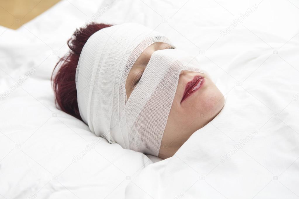 closeup of woman in bed with bandages wrapped around her head