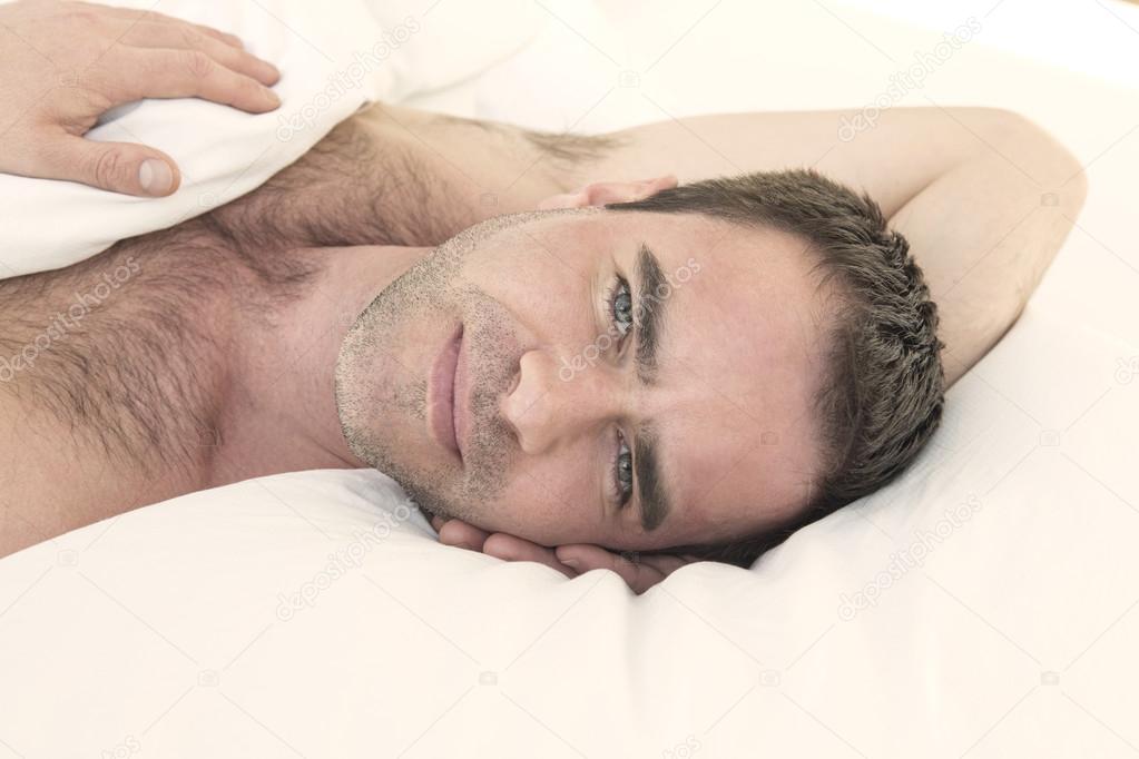 shirtless man in bed and smiling