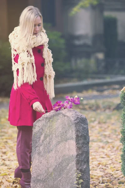 Woman putting a flower on tombstone — Stock Photo, Image